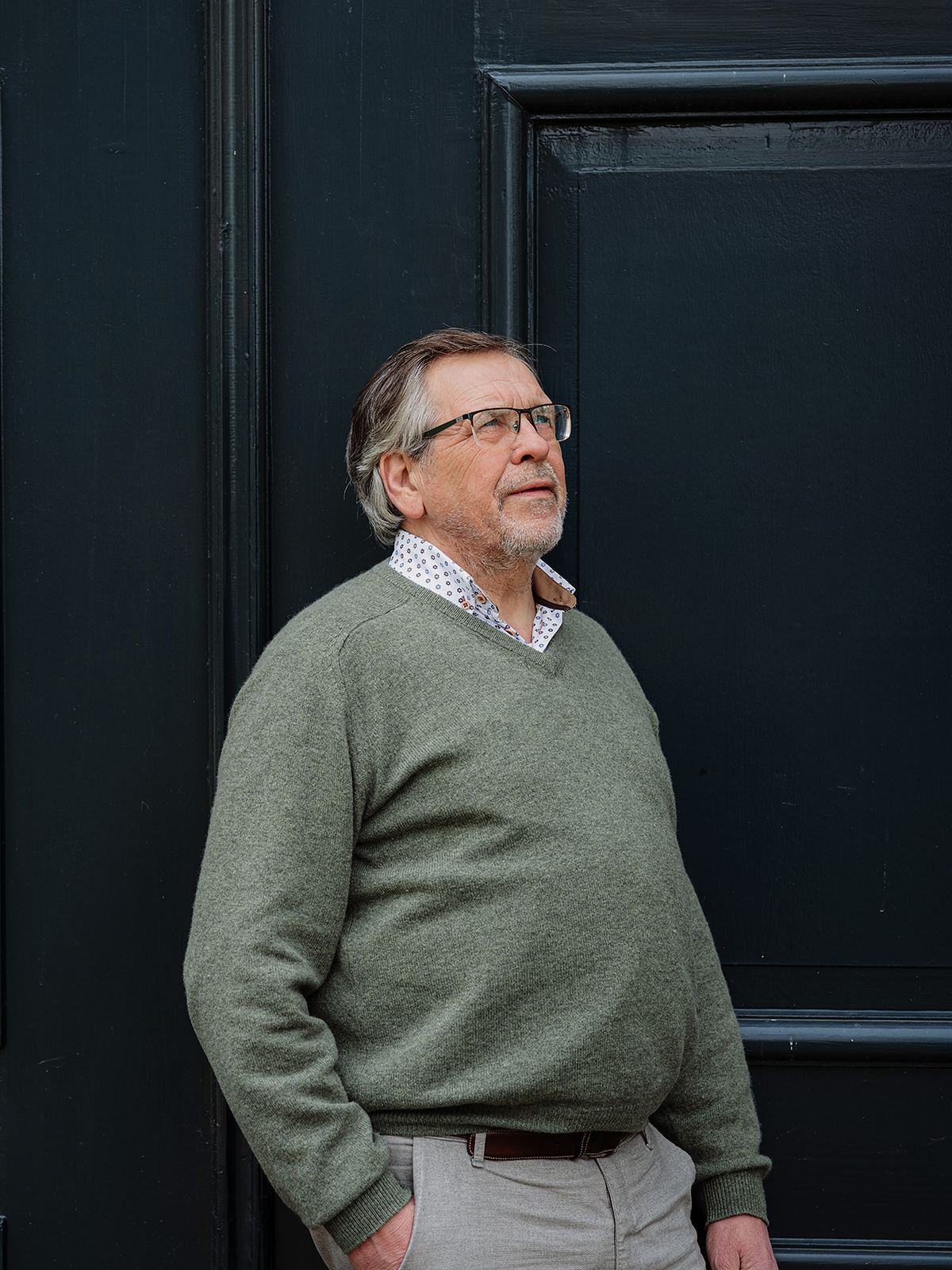 Walter Baars staat voor een donkergroene deur en kijkt omhoog