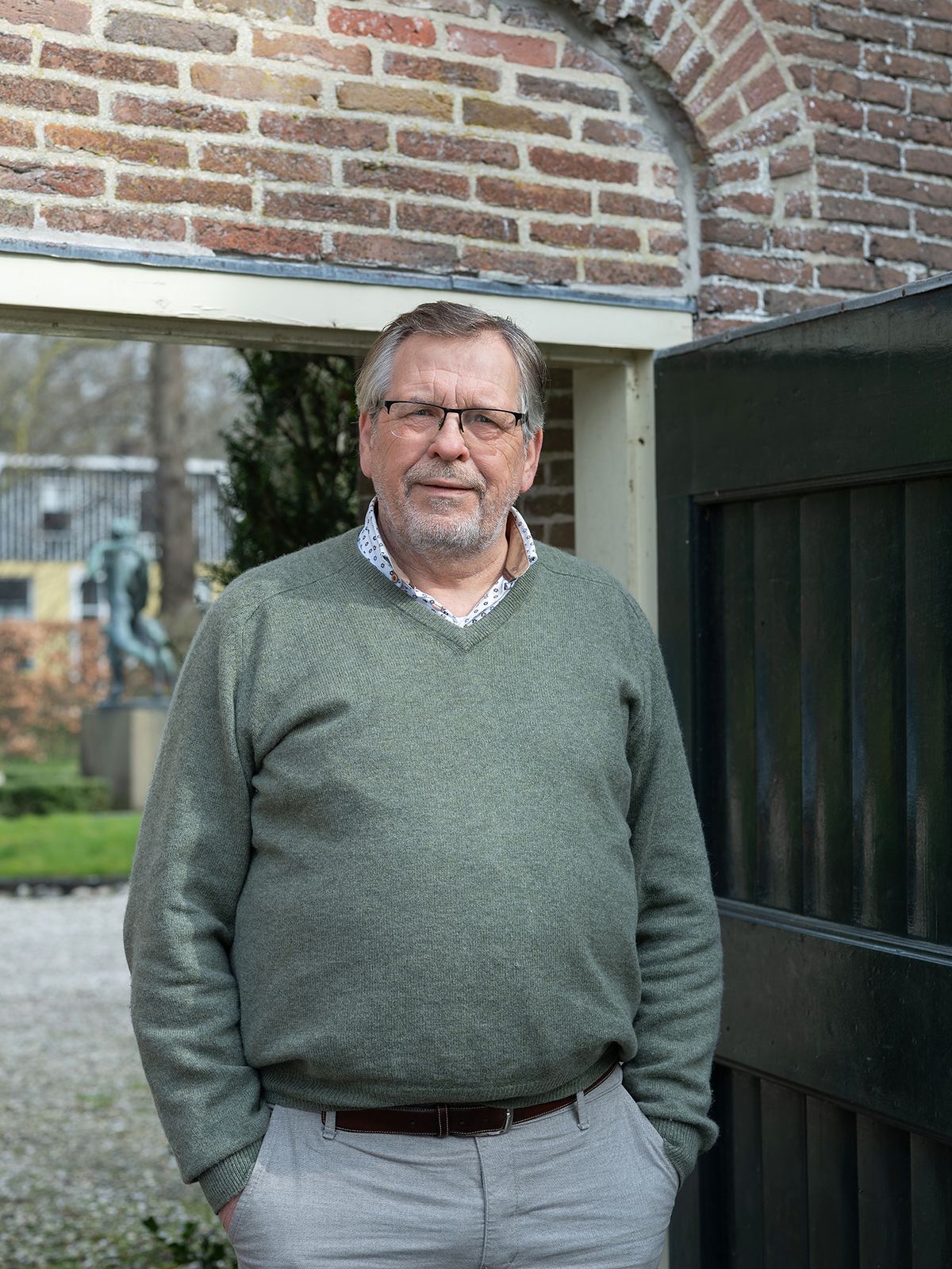 Walter Baars in een open deuropening, het erf achter hem